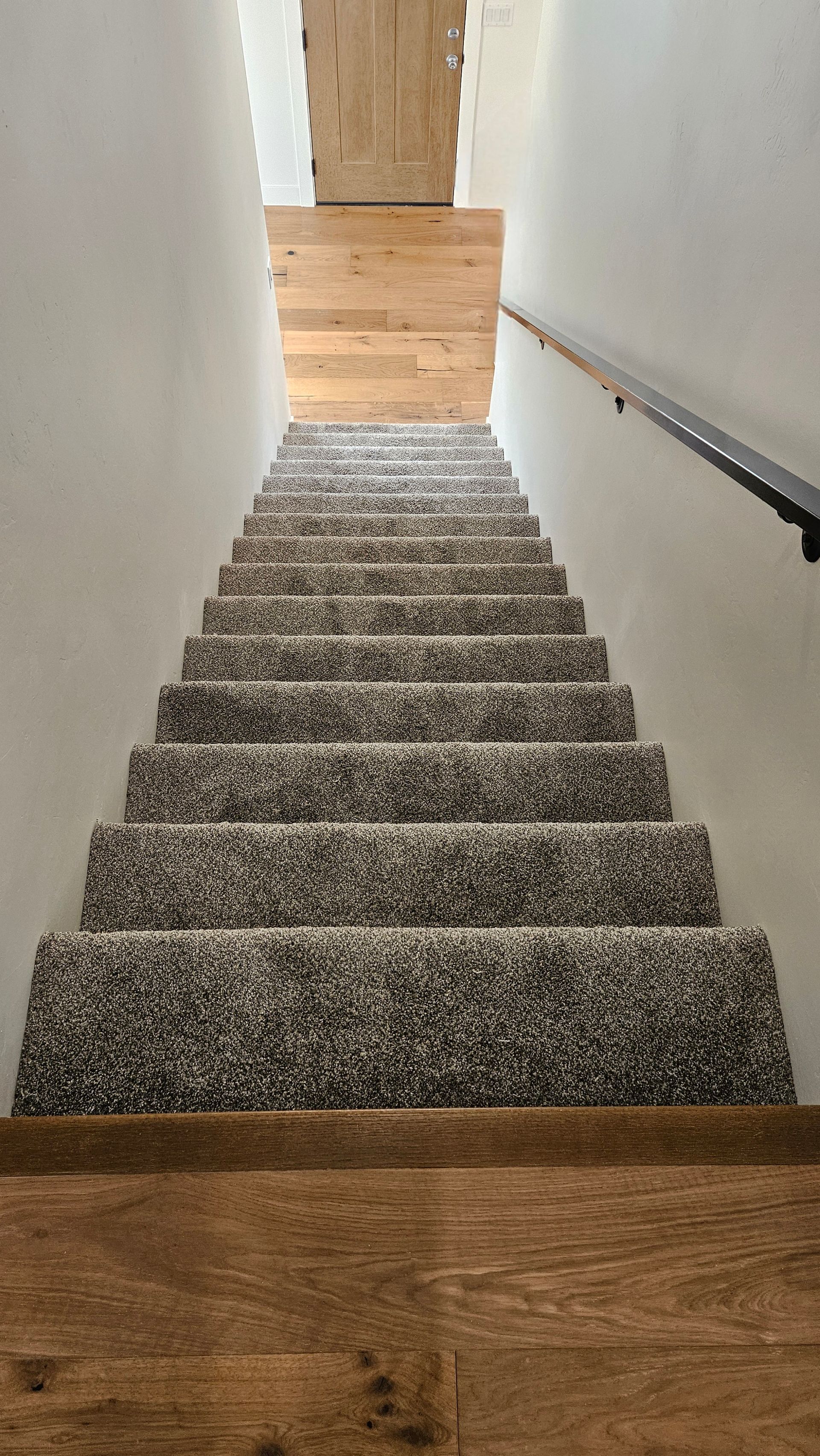 A staircase with a carpeted staircase and a wooden floor