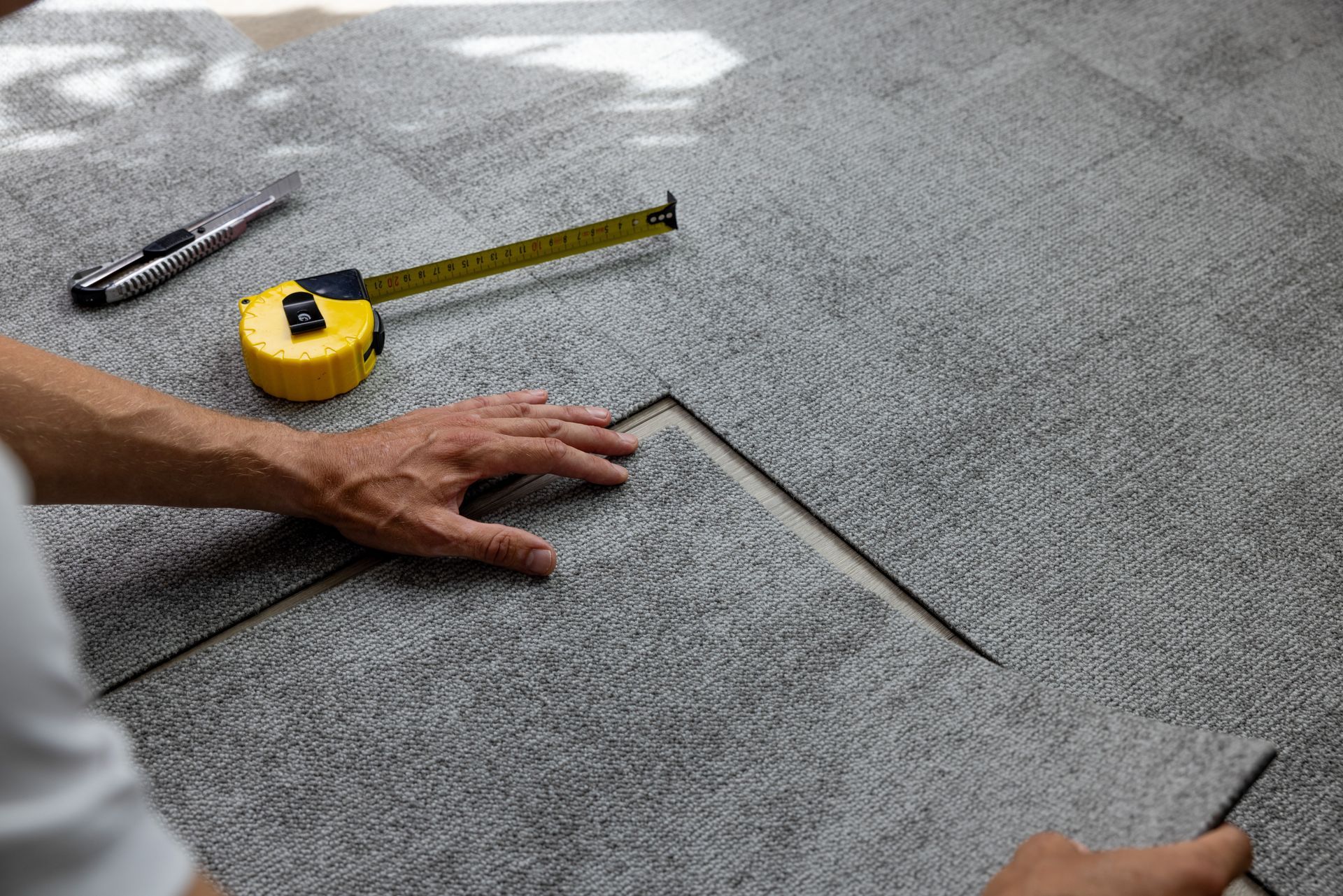 A person is measuring a piece of carpet with a tape measure.