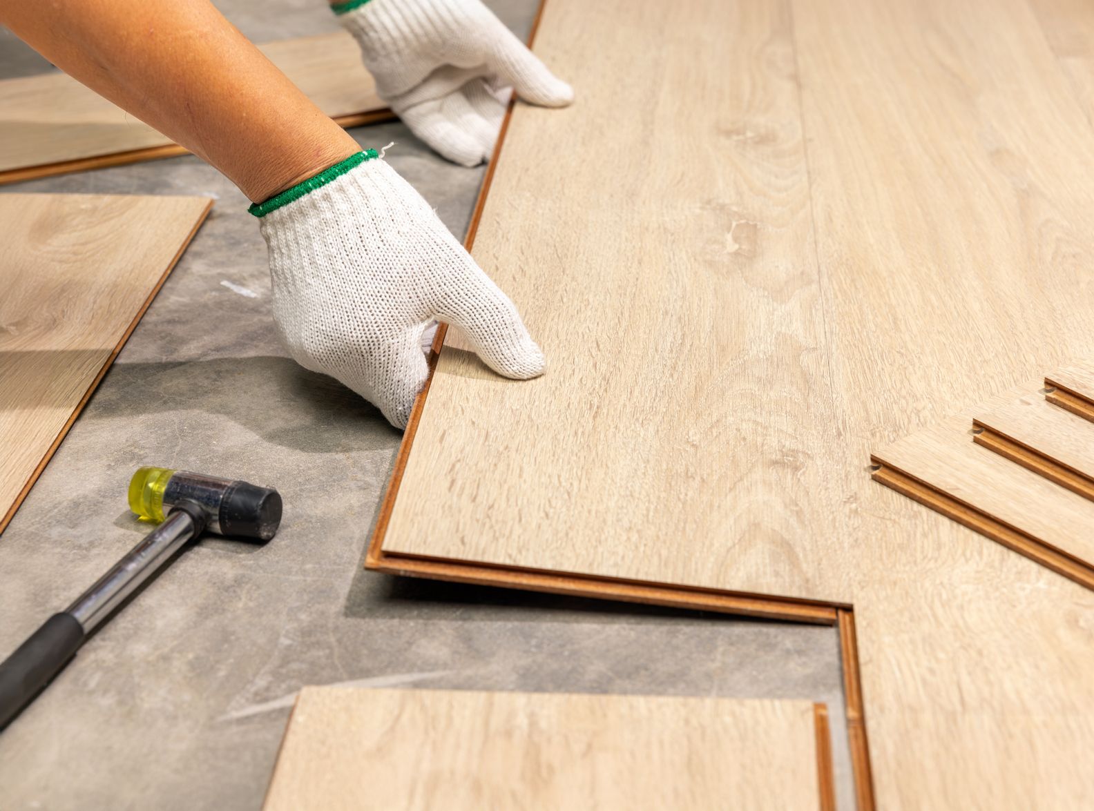 A person is installing a wooden floor with a hammer.