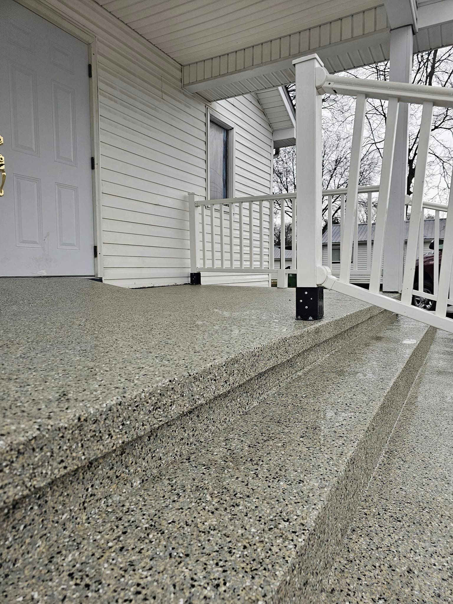 A porch with stairs leading up to it and a white railing.