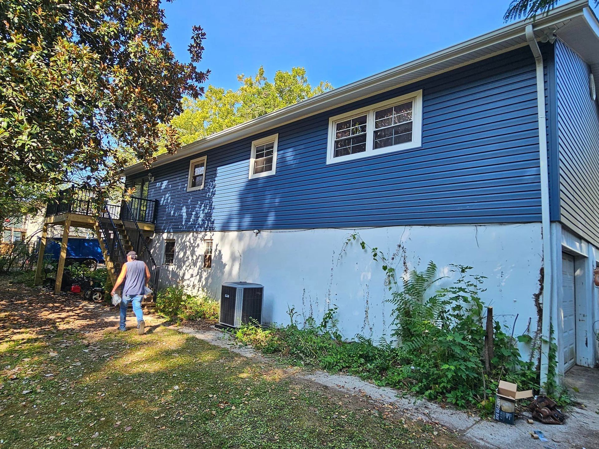 A woman is walking in front of a blue house.
