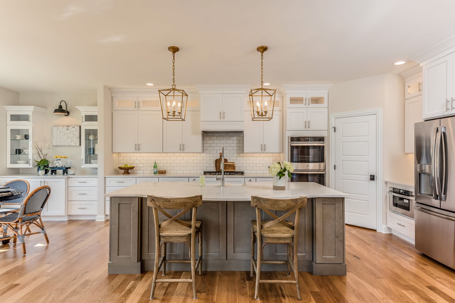A kitchen with white cabinets, appliances, hardwood floors.