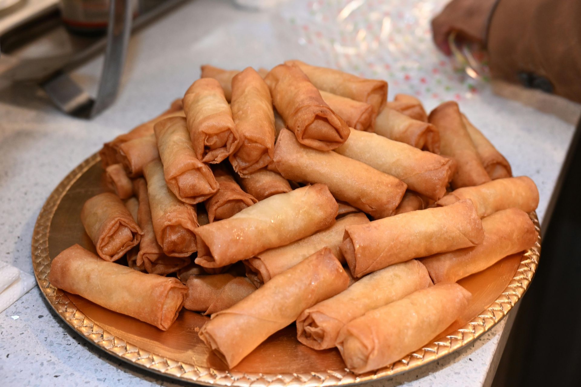 A plate piled high with golden-brown, crispy spring rolls.