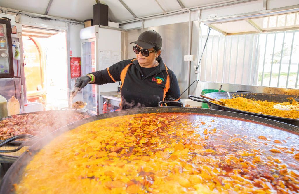 A woman is cooking a large amount of food in a large pan.