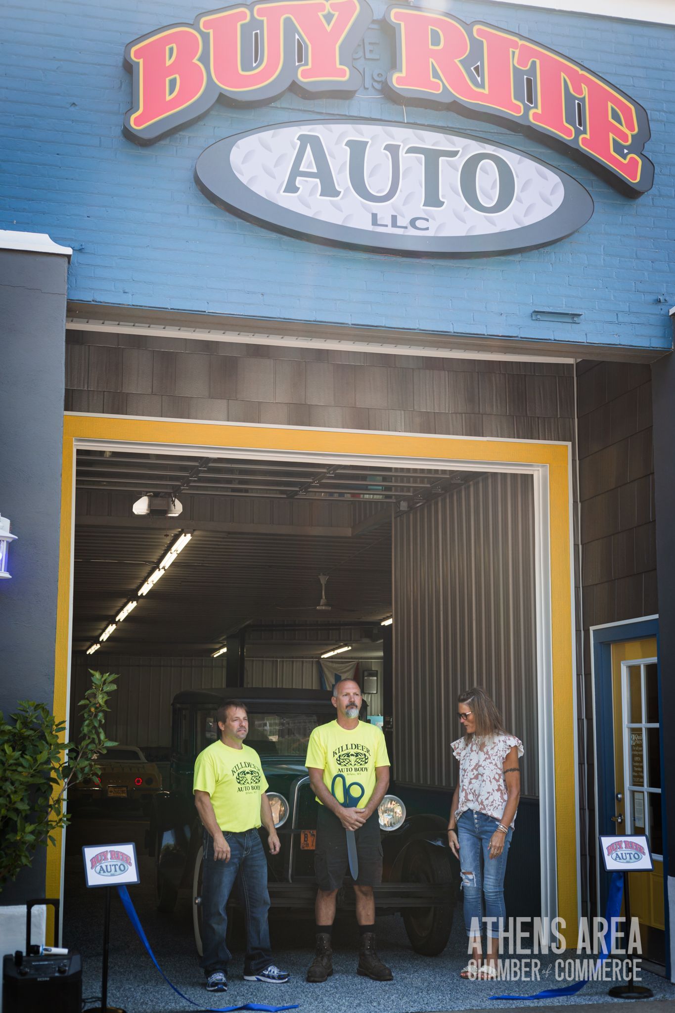 A group of people standing in front of a building that says buy rite auto