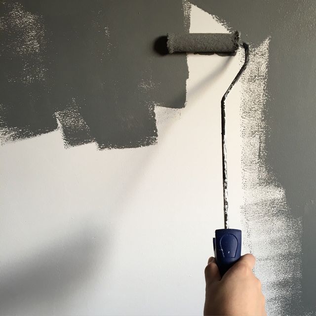 A person is painting a wall with a paint roller
