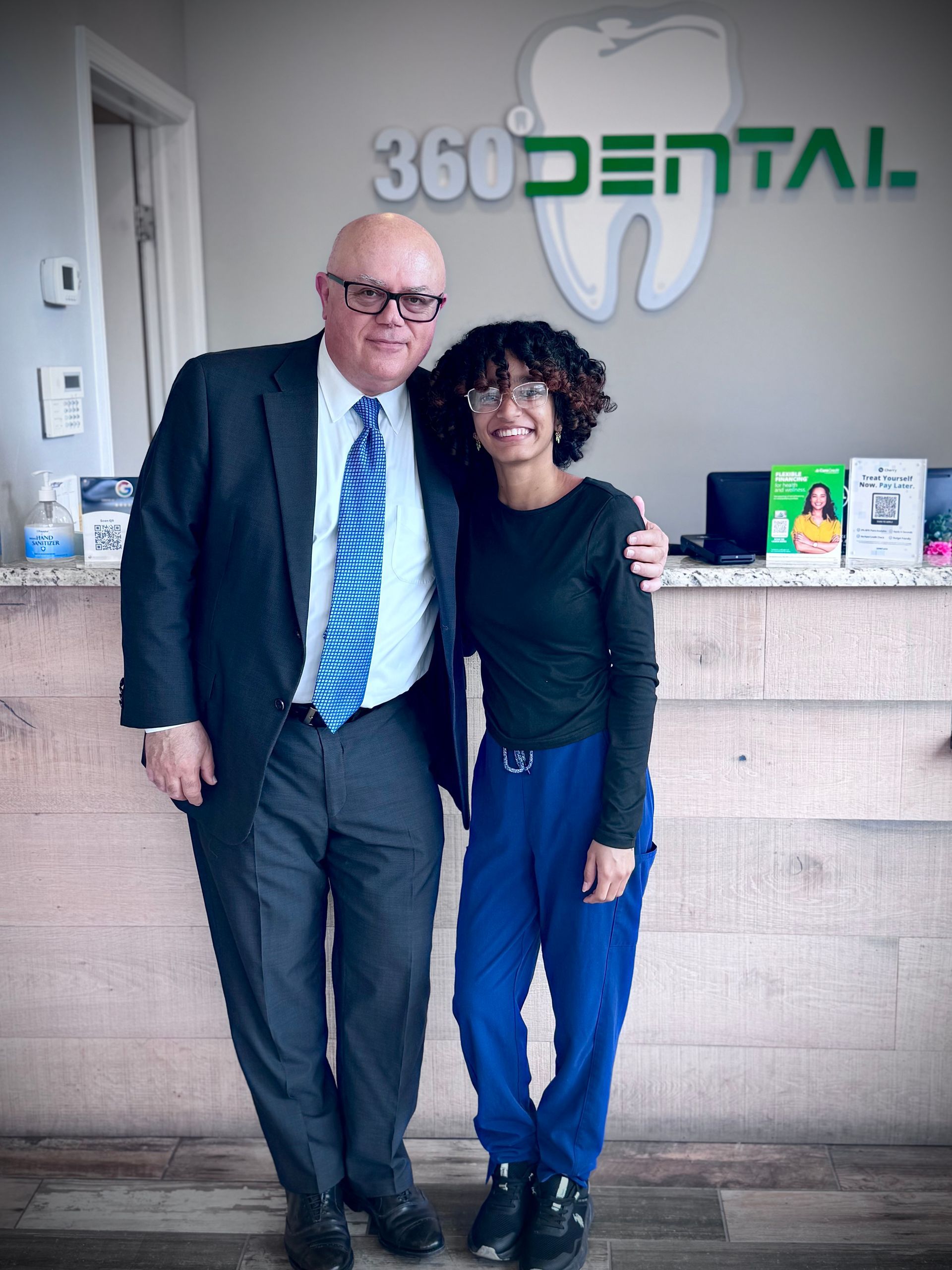 A group of women are posing for a picture in front of a sign that says 360 dental