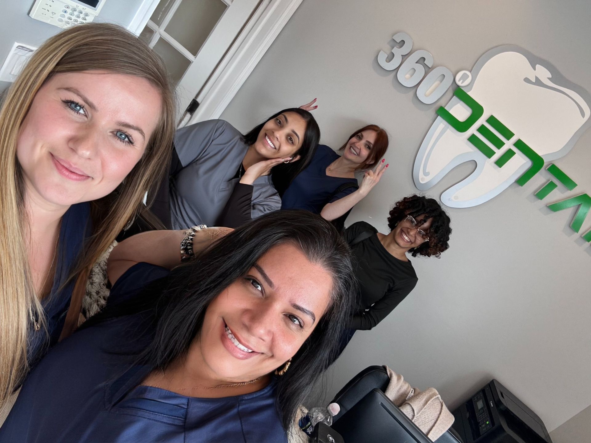 A group of women are posing for a picture in front of a sign that says 360 dental