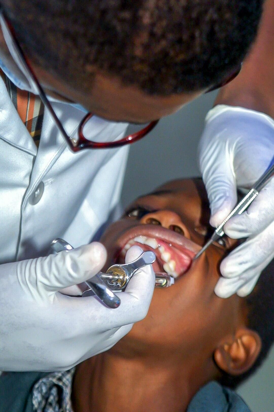 Dentist administering an injection into a patient's mouth, dental tools visible.