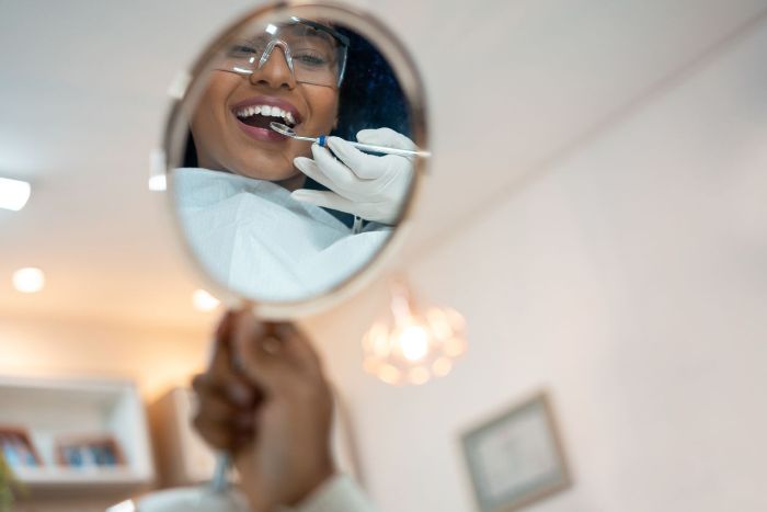 A woman is looking at her teeth in a mirror.