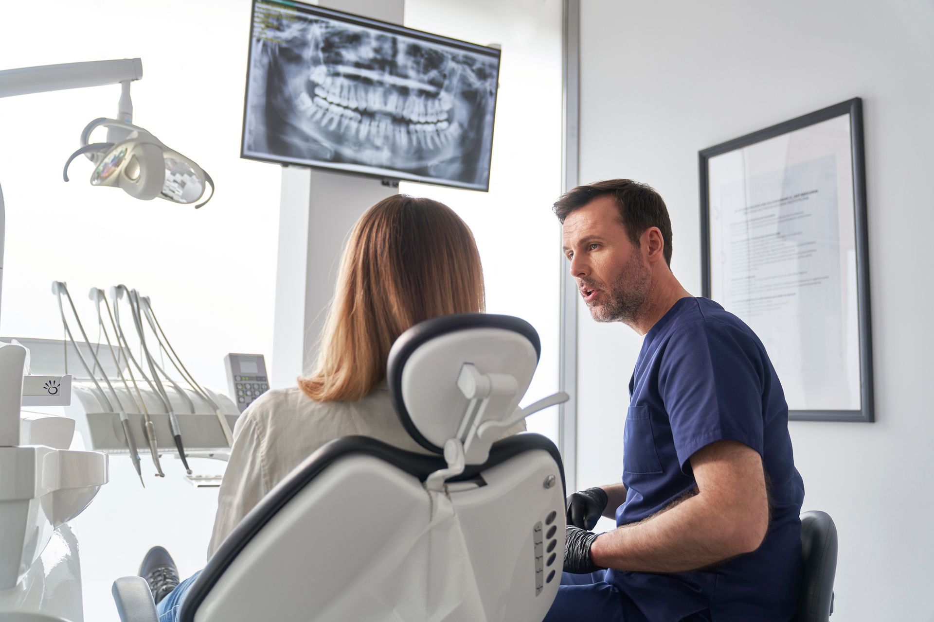 A dentist is talking to a patient in a dental chair.
