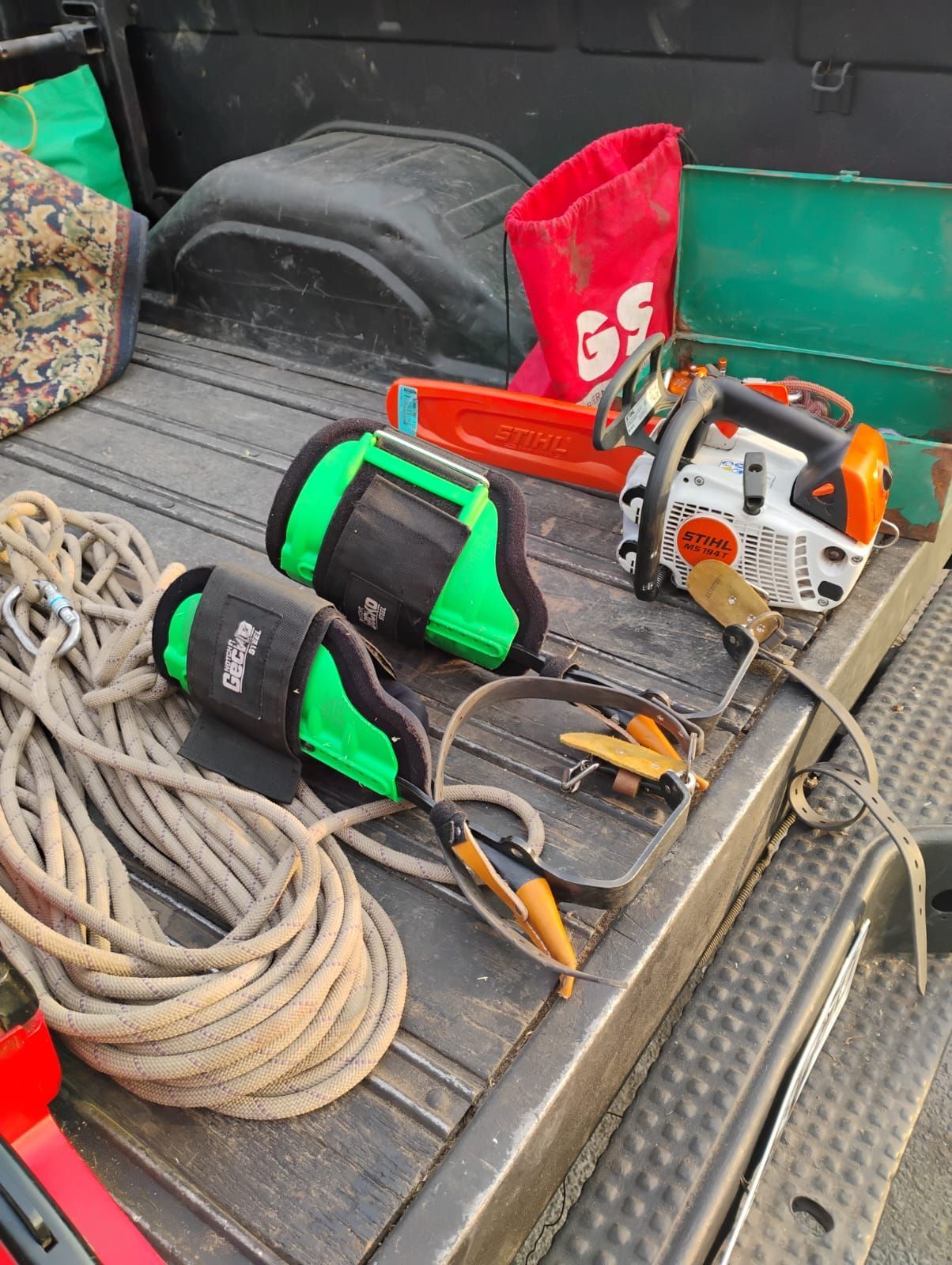 Una caja de camión llena de cuerdas, motosierras y otras herramientas.