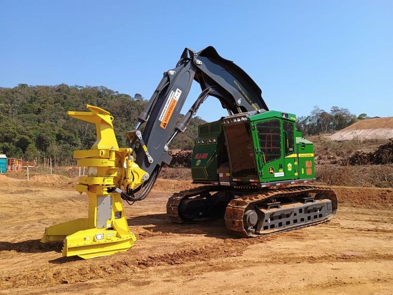 Um trator verde e amarelo está estacionado em um campo de terra