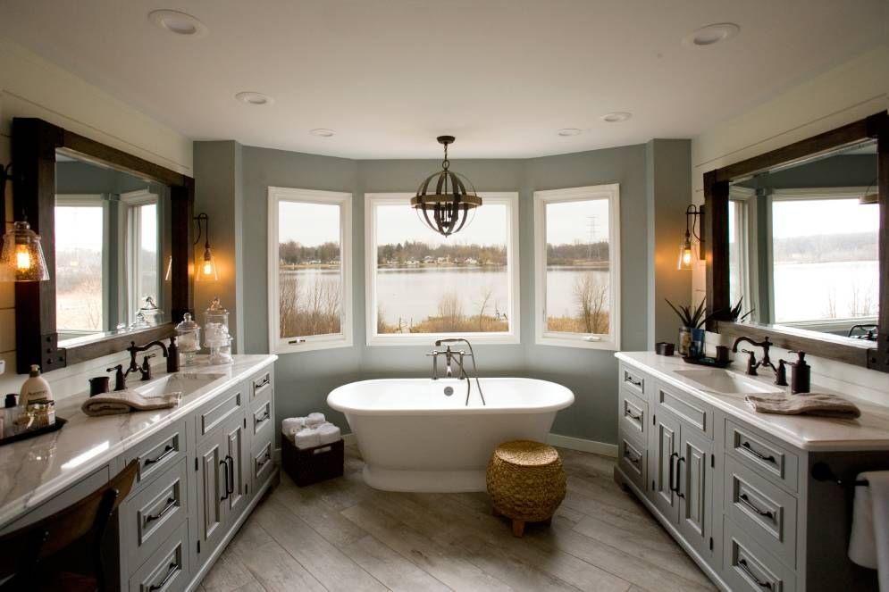 A bathroom with two sinks , a tub , and two mirrors.