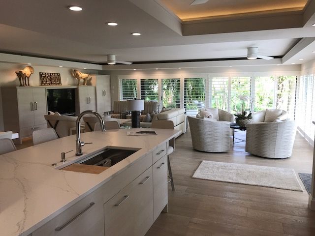 A kitchen with a sink and a living room in the background