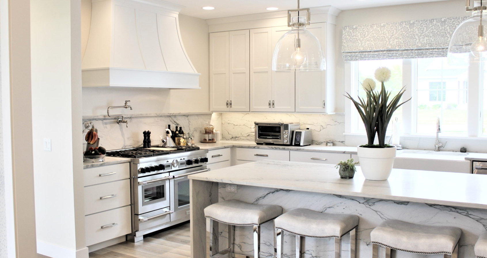 A kitchen with white cabinets , stainless steel appliances , and a large island.