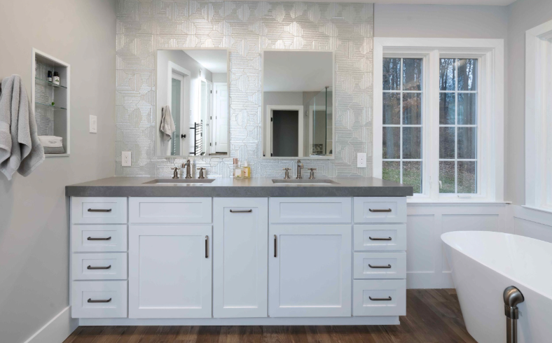 A bathroom with two sinks , a tub and a window.