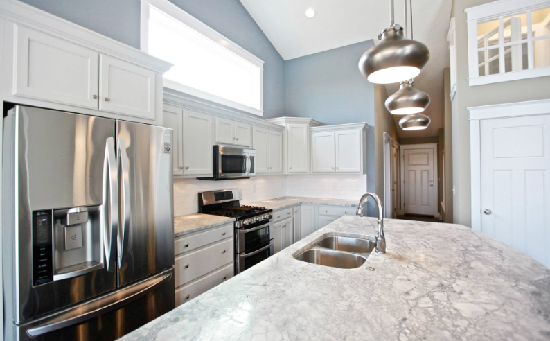 A kitchen with white cabinets , stainless steel appliances and granite counter tops.