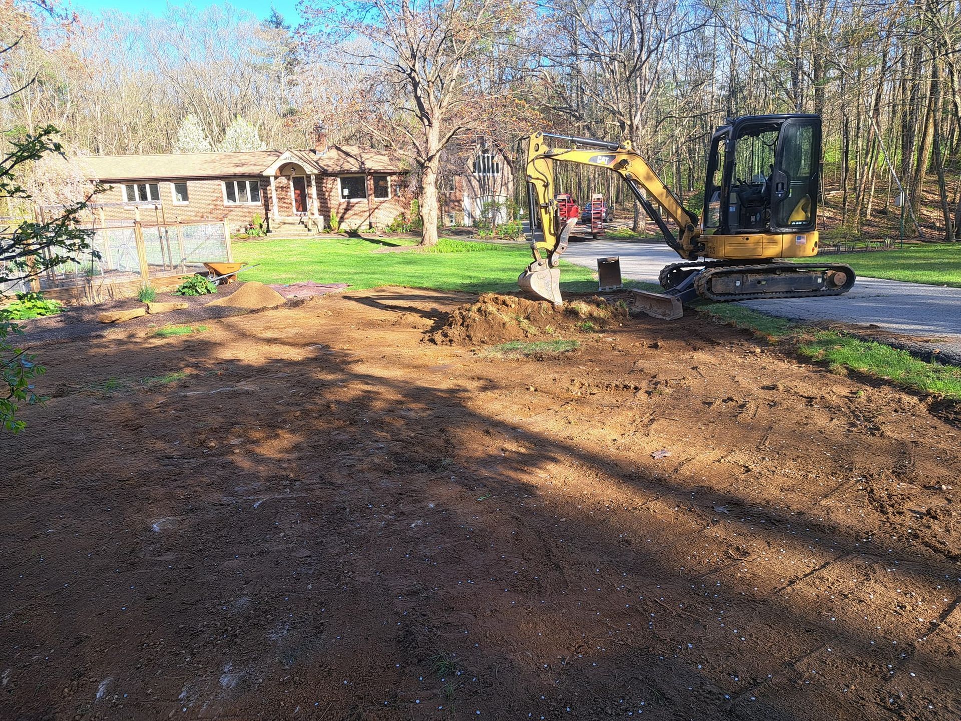 A yellow excavator is digging a hole in the dirt in front of a house.
