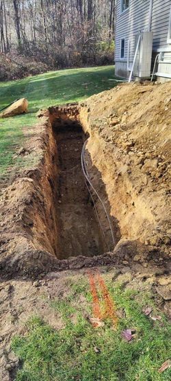 A large hole in the ground in a yard next to a house.
