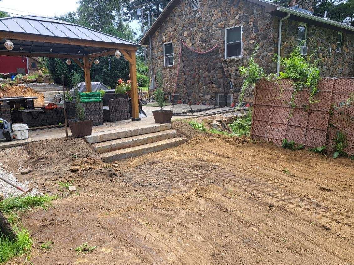 A dirt yard in front of a stone house.