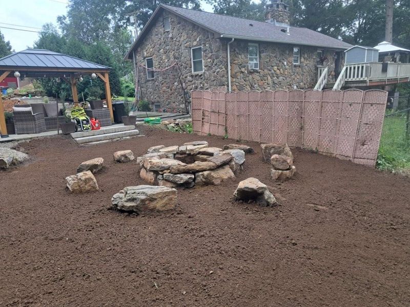 There is a fire pit in the middle of the yard in front of a stone house.