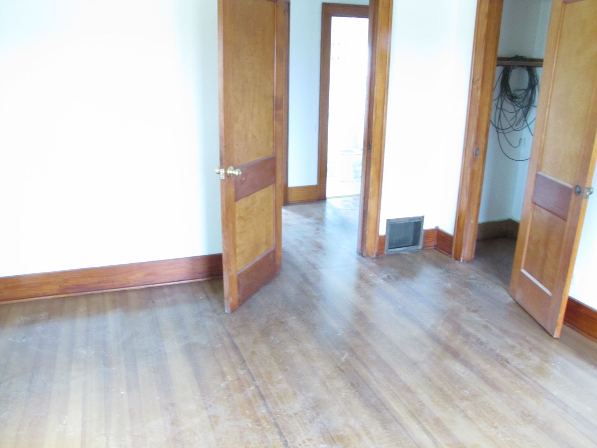 An empty room with hardwood floors and wooden doors