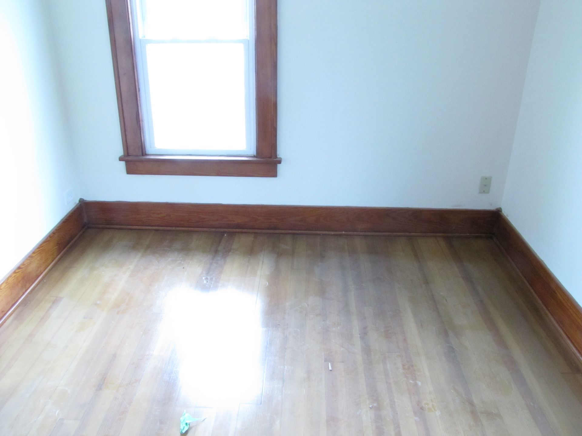 An empty room with hardwood floors and a window