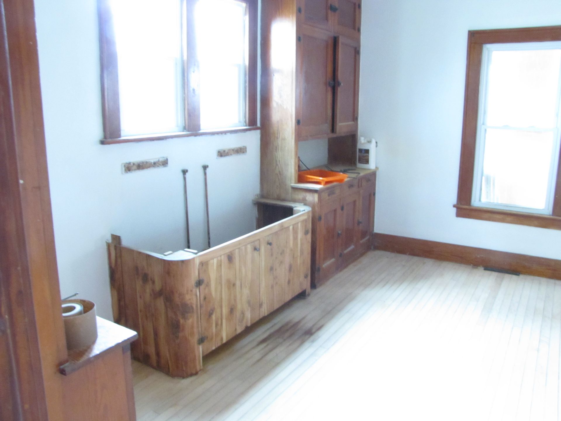 An empty room with a wooden bathtub and a window