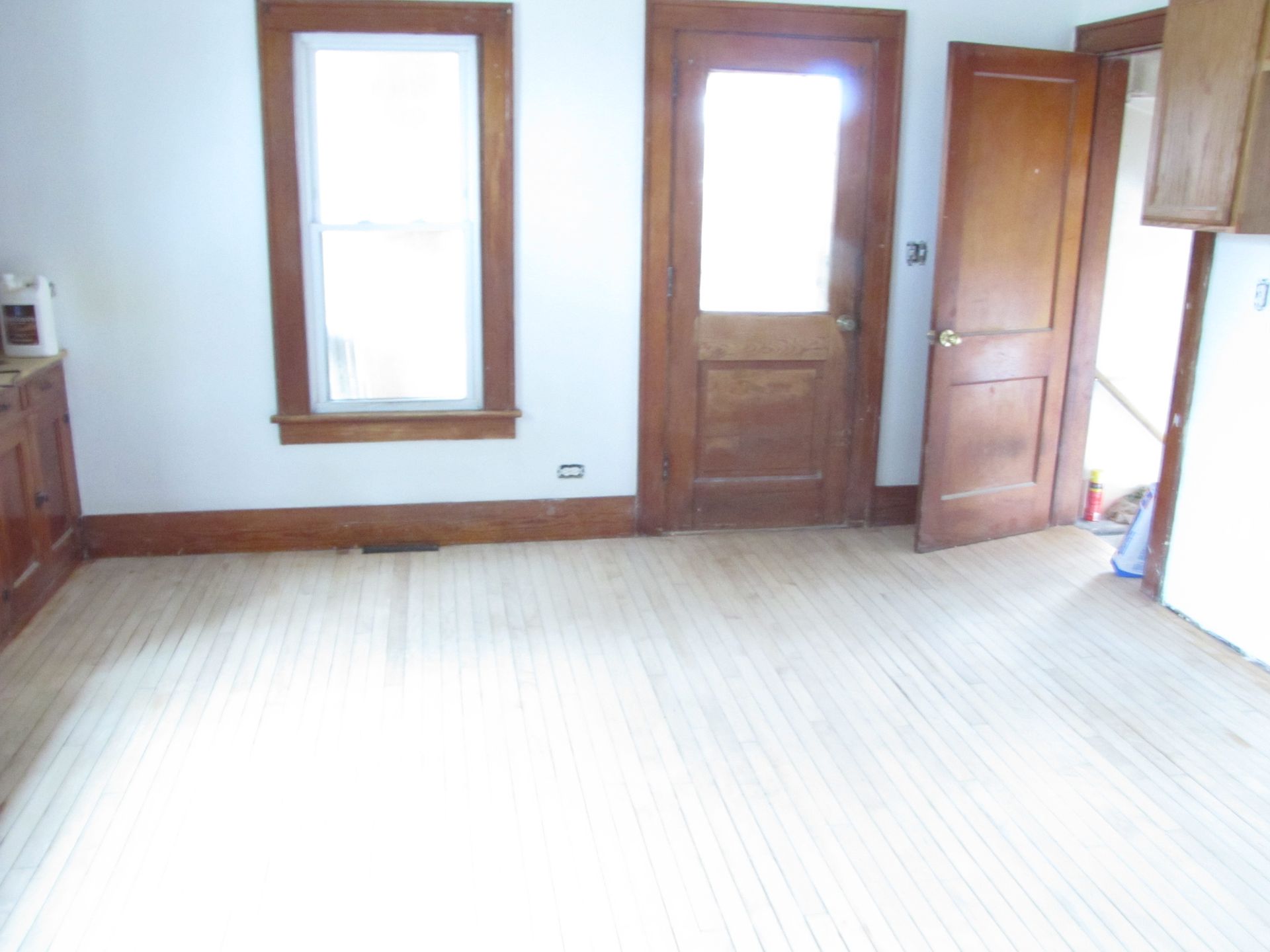 An empty room with a door and two windows