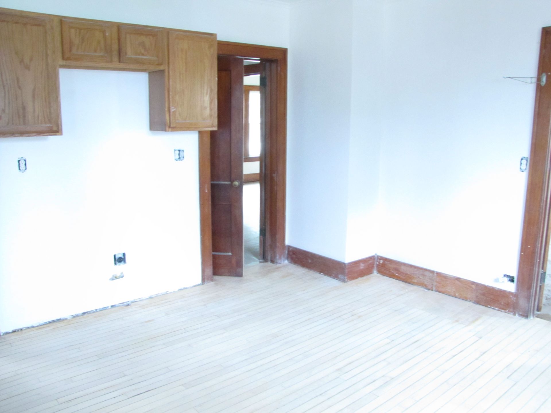 An empty room with white walls and wooden cabinets