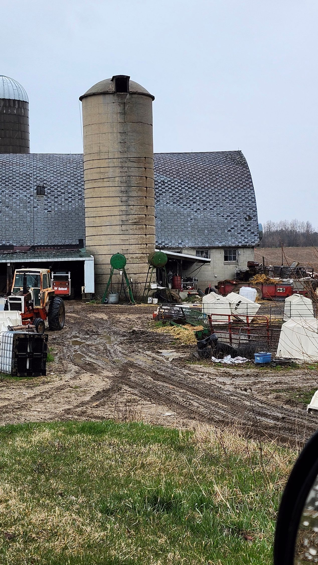 A farm with a silo and a tractor in front of it.