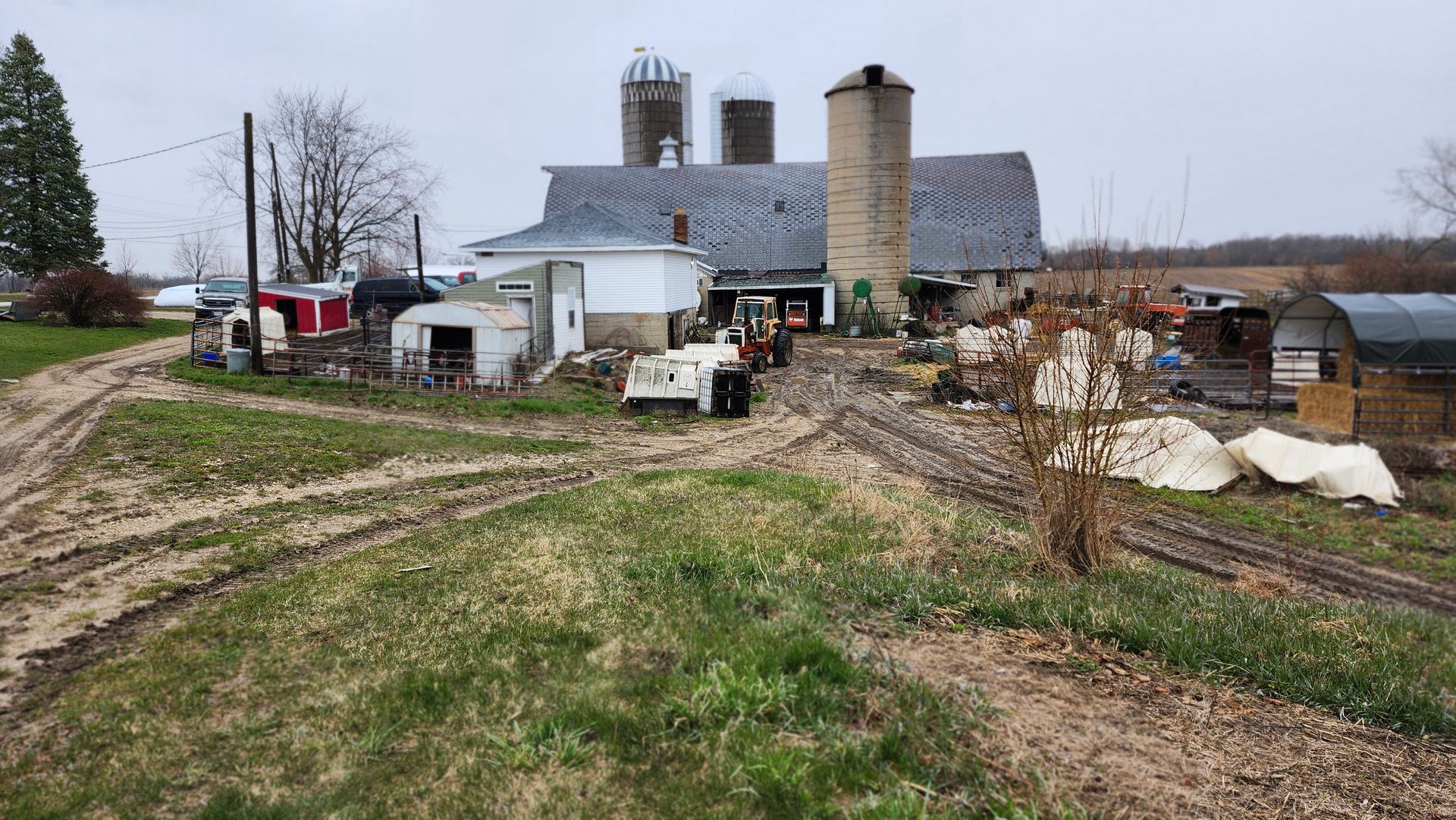A farm with a barn and silos in the middle of a field.
