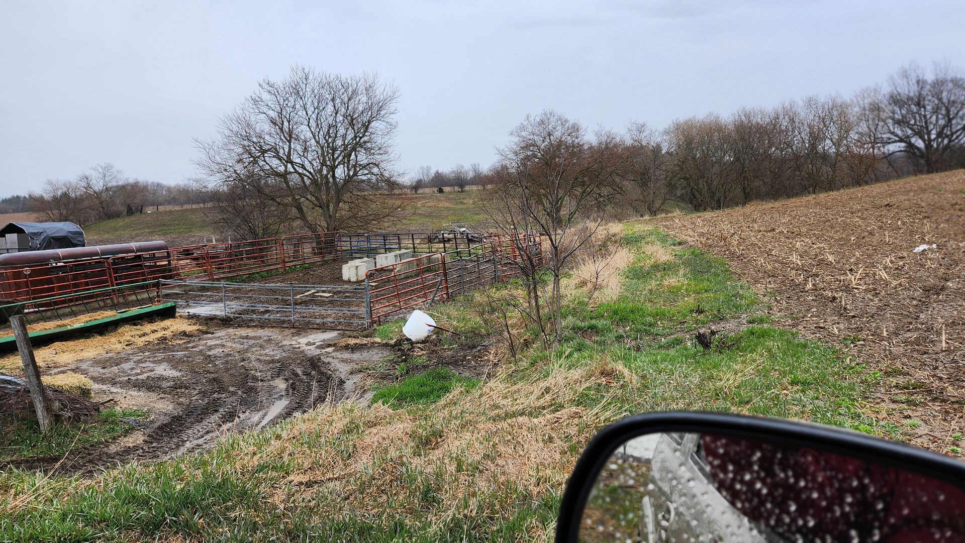 A car is driving down a dirt road next to a field.