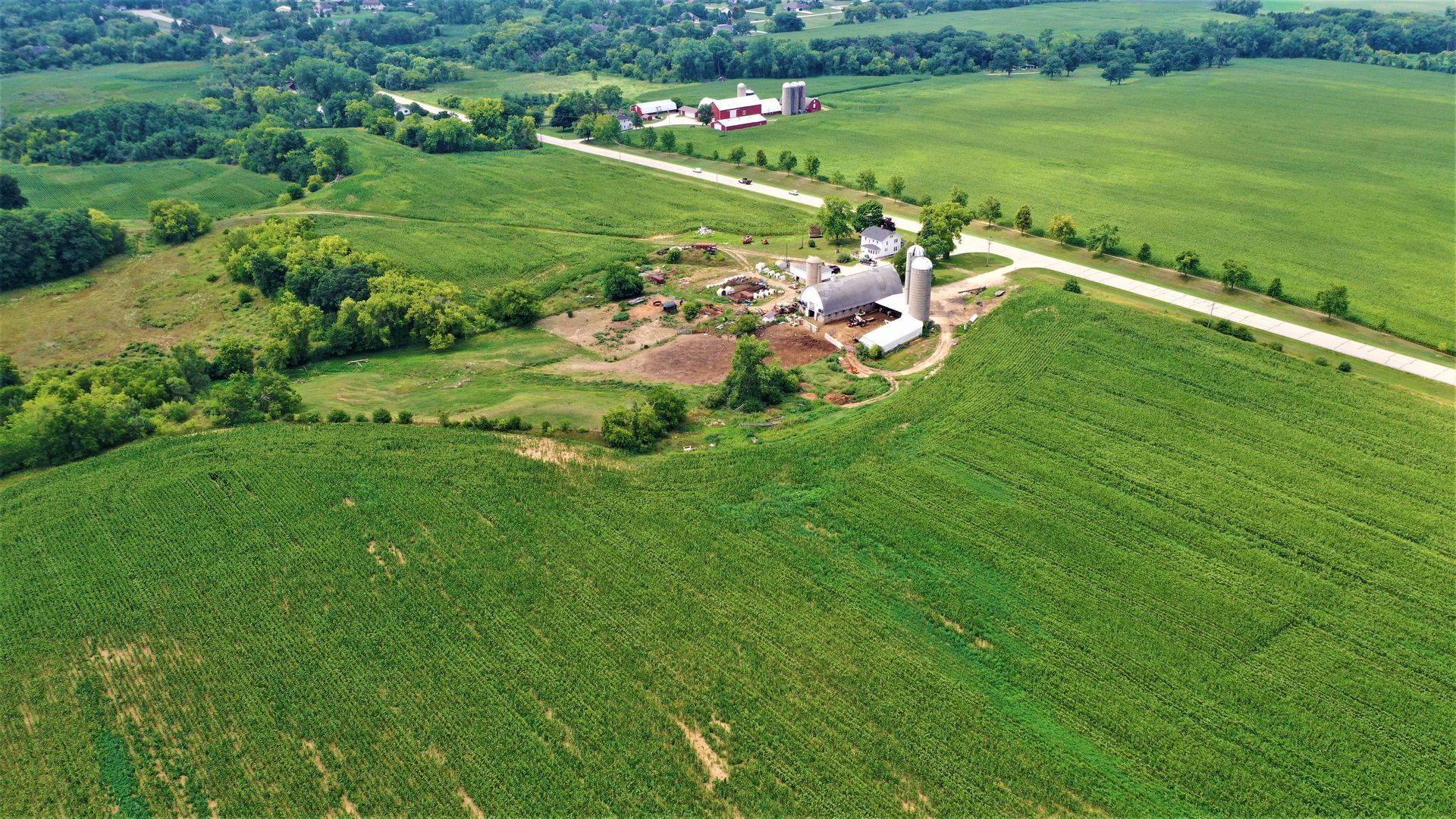 An aerial view of a farm with a silo in the middle of a field.