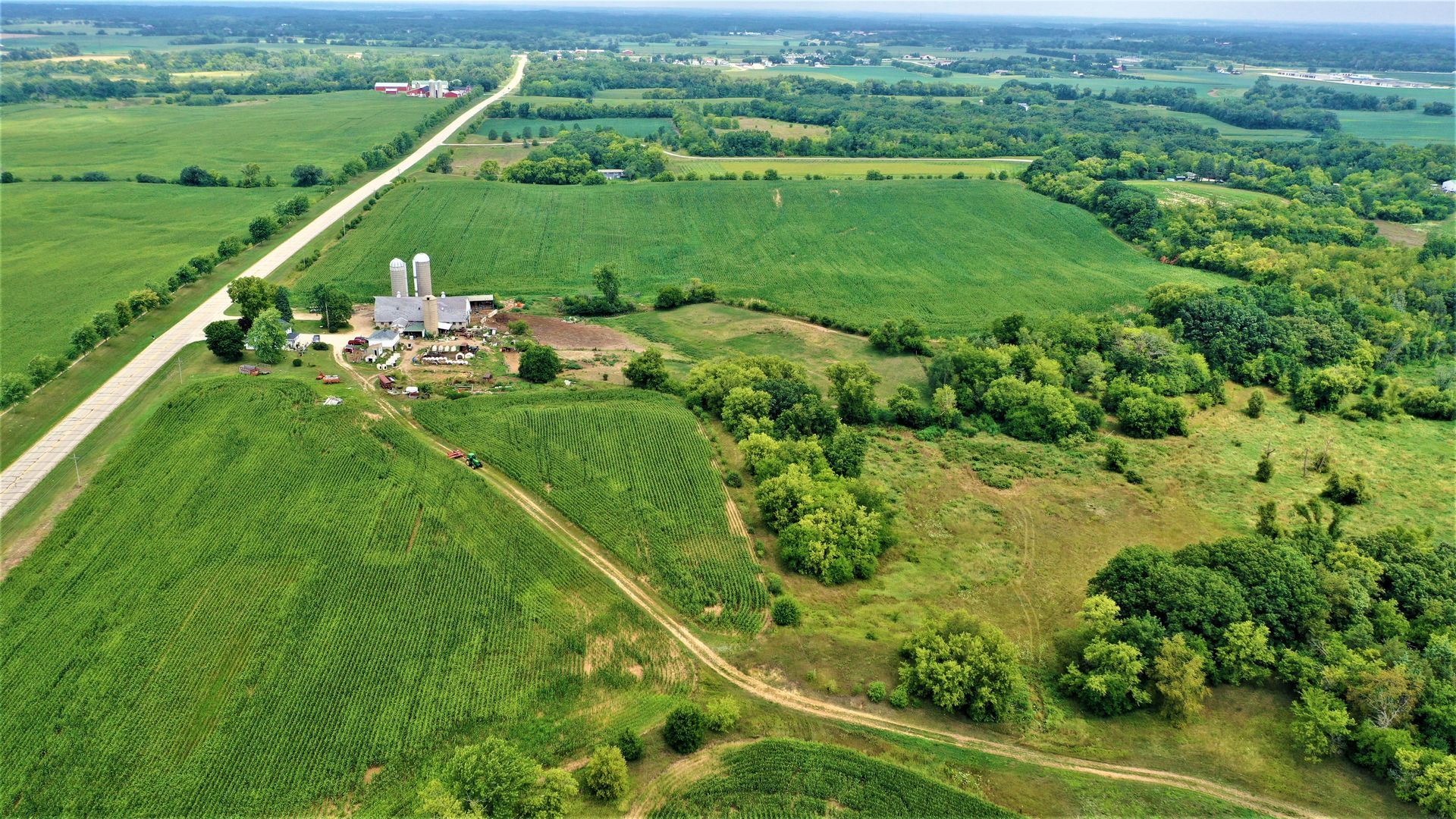 An aerial view of a farm surrounded by lush green fields and trees.