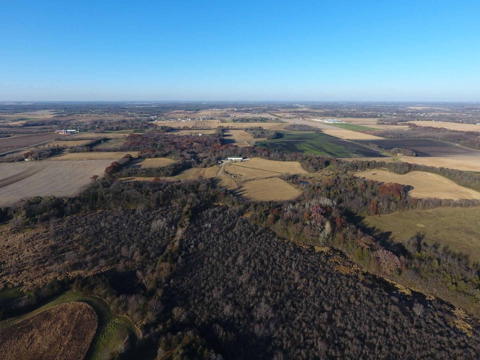 An aerial view of a lush green forest surrounded by fields and trees.