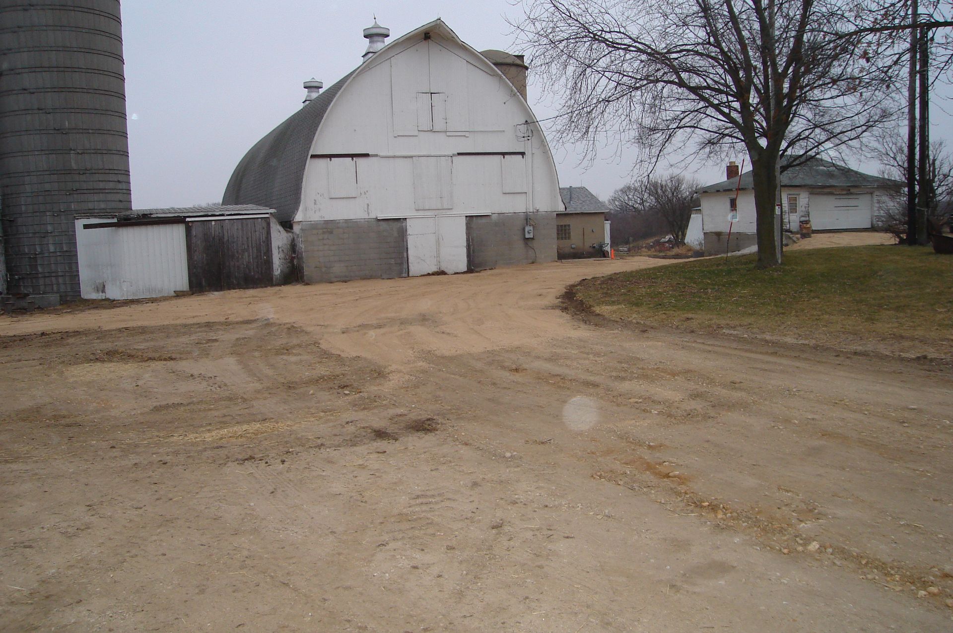 A dirt road leads to a white barn