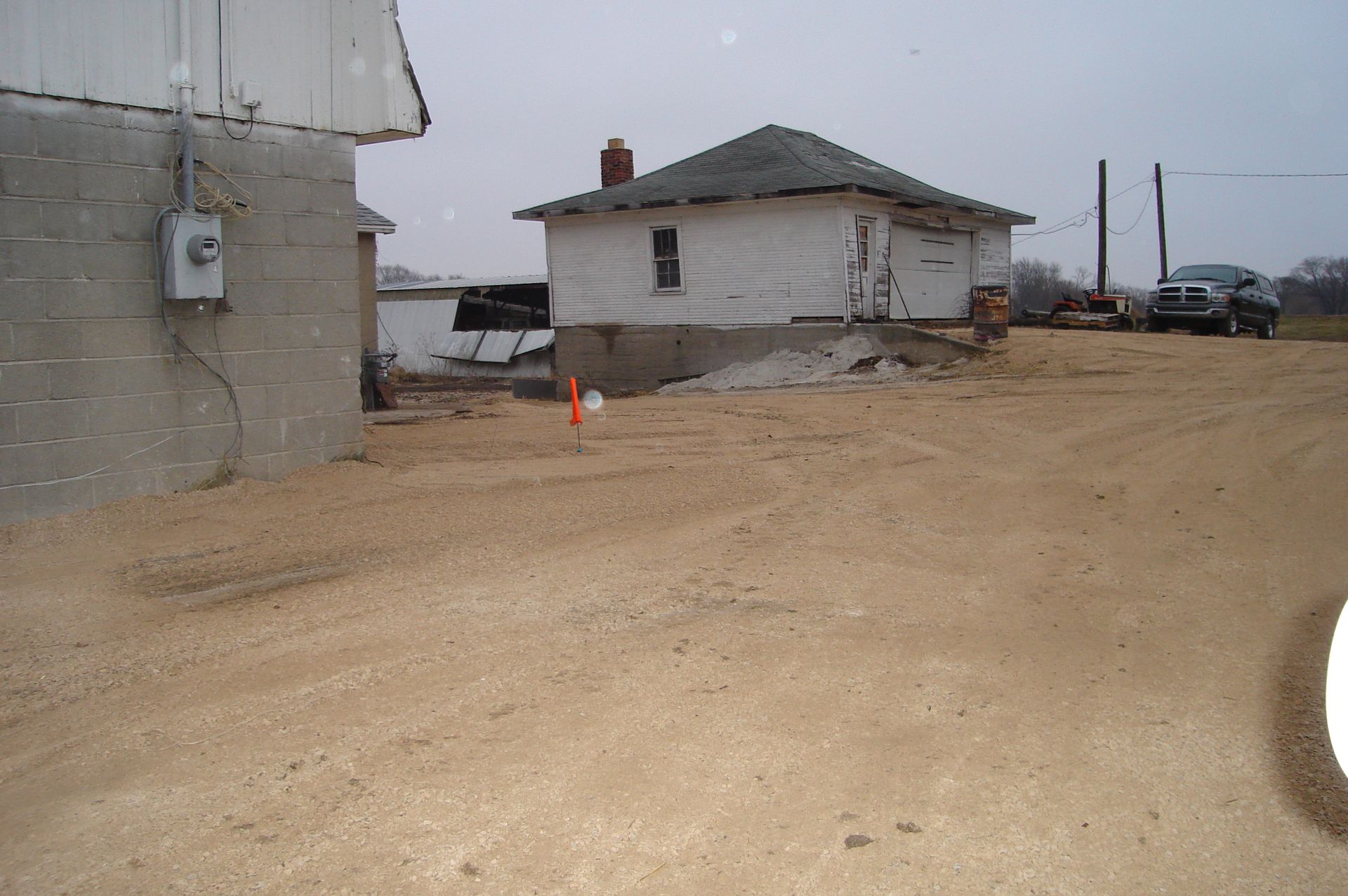 A white house sits in the middle of a dirt field