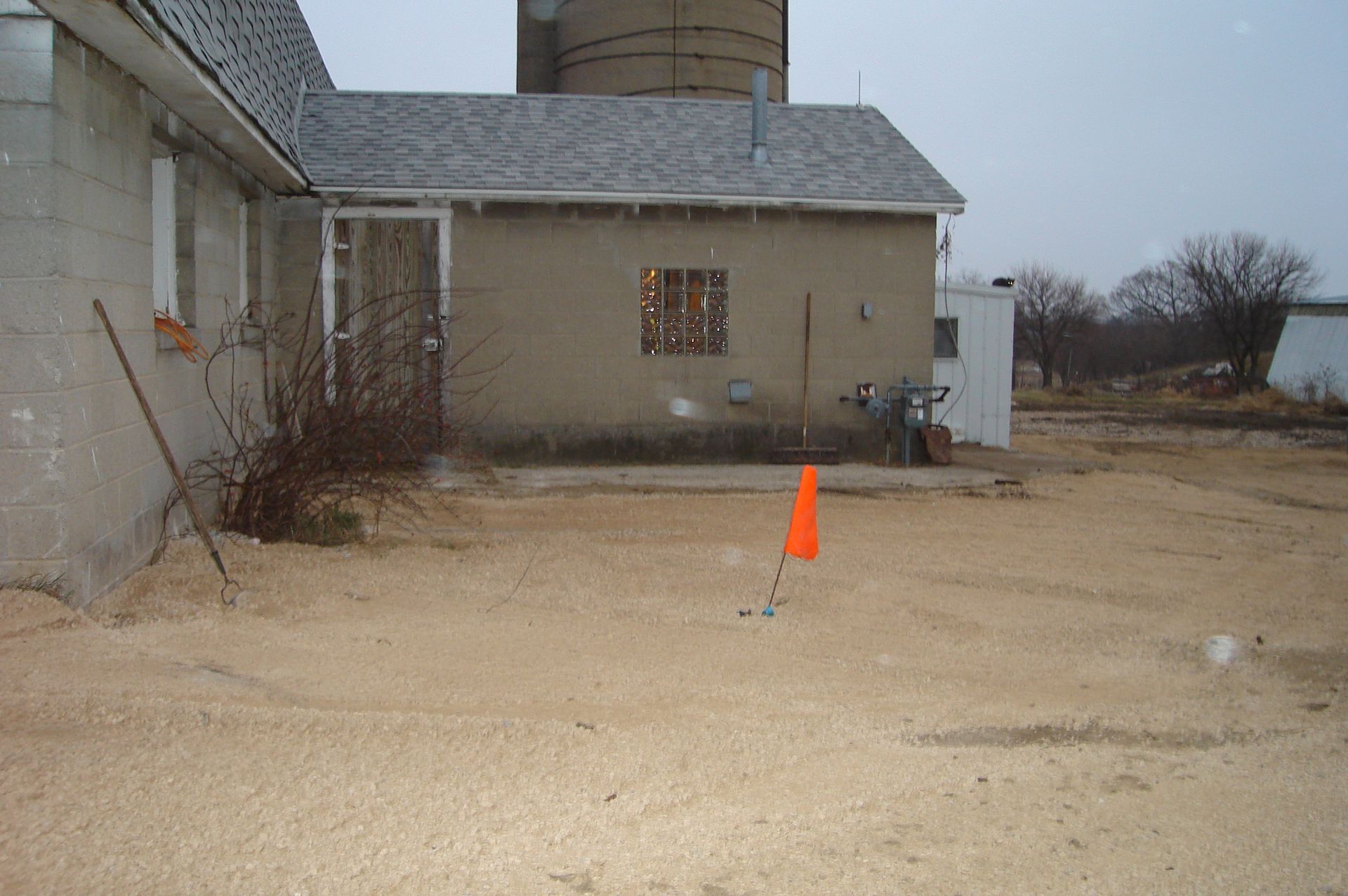 An orange cone is in the dirt in front of a building