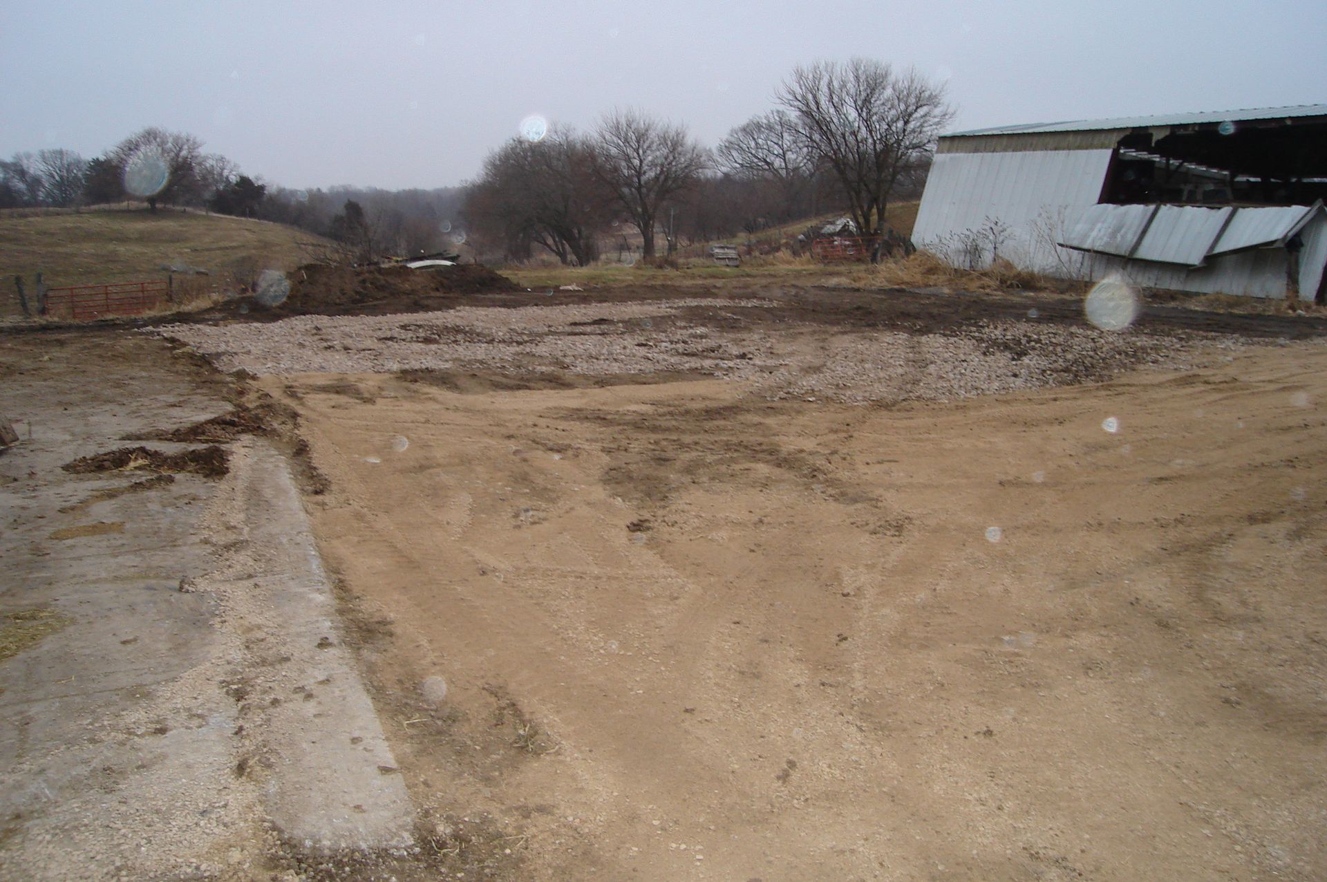 A dirt field with a white building in the background