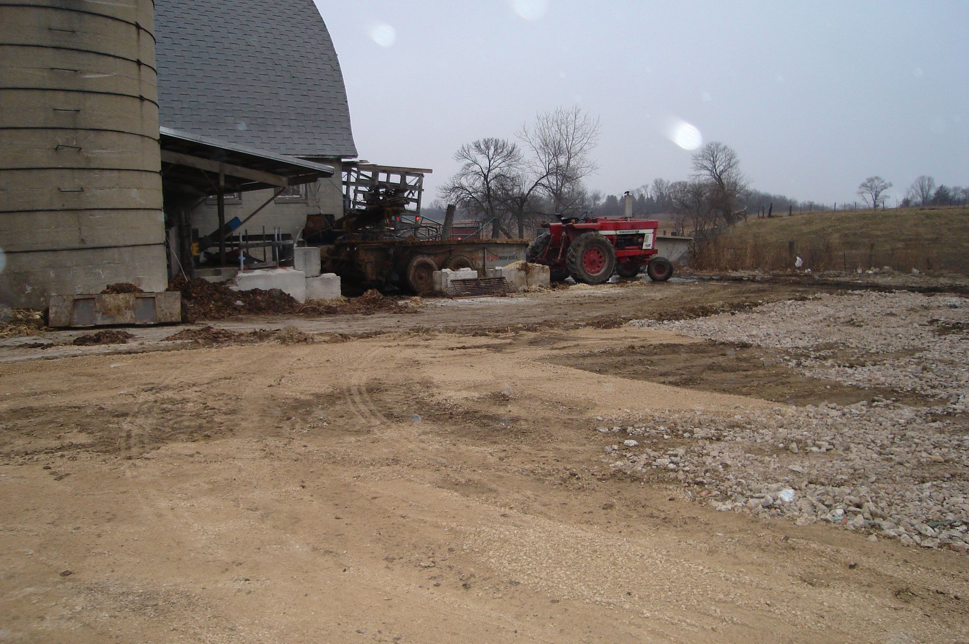 A red tractor is parked in front of a silo