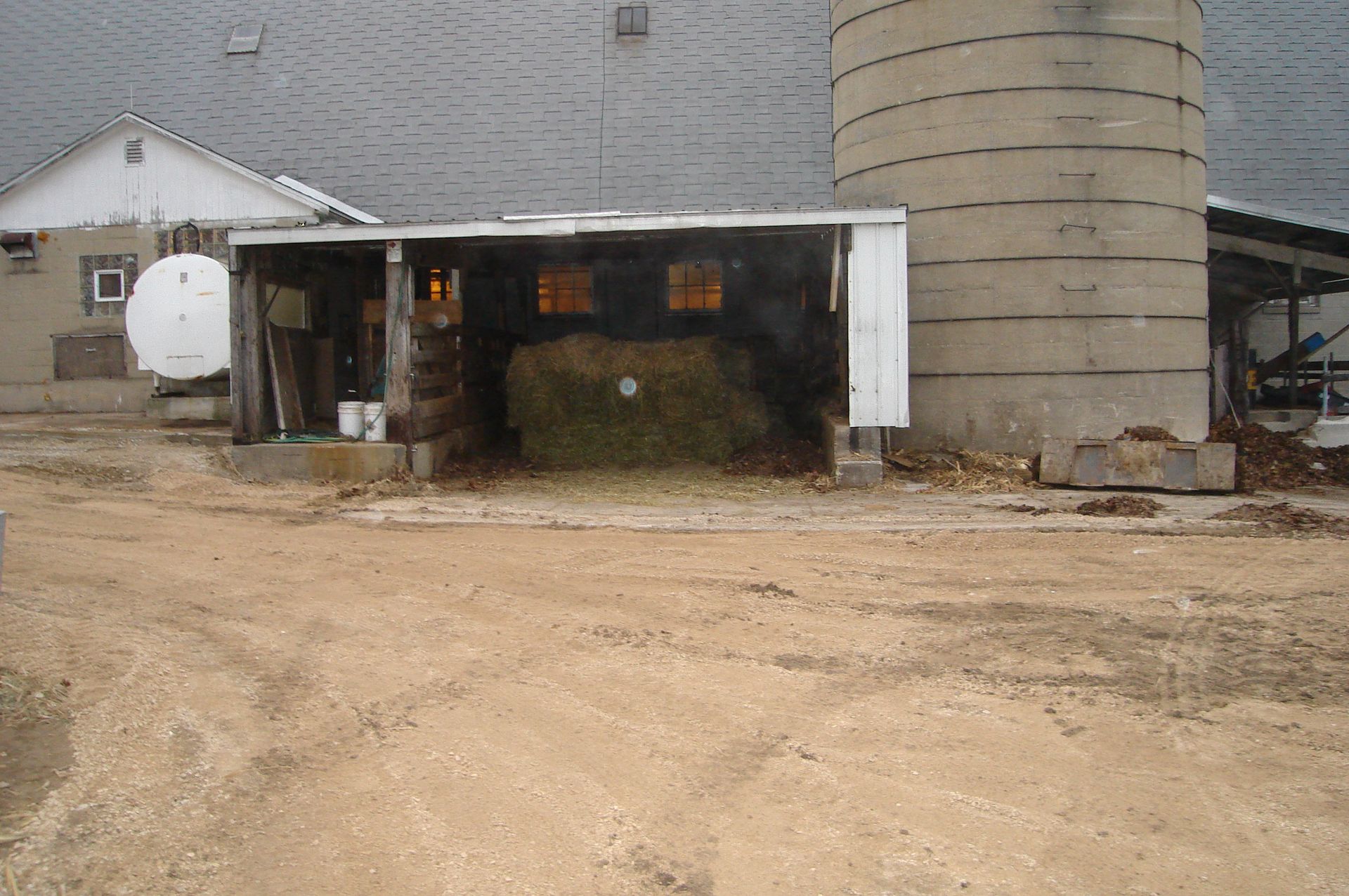 A barn with a shed and a silo in the background