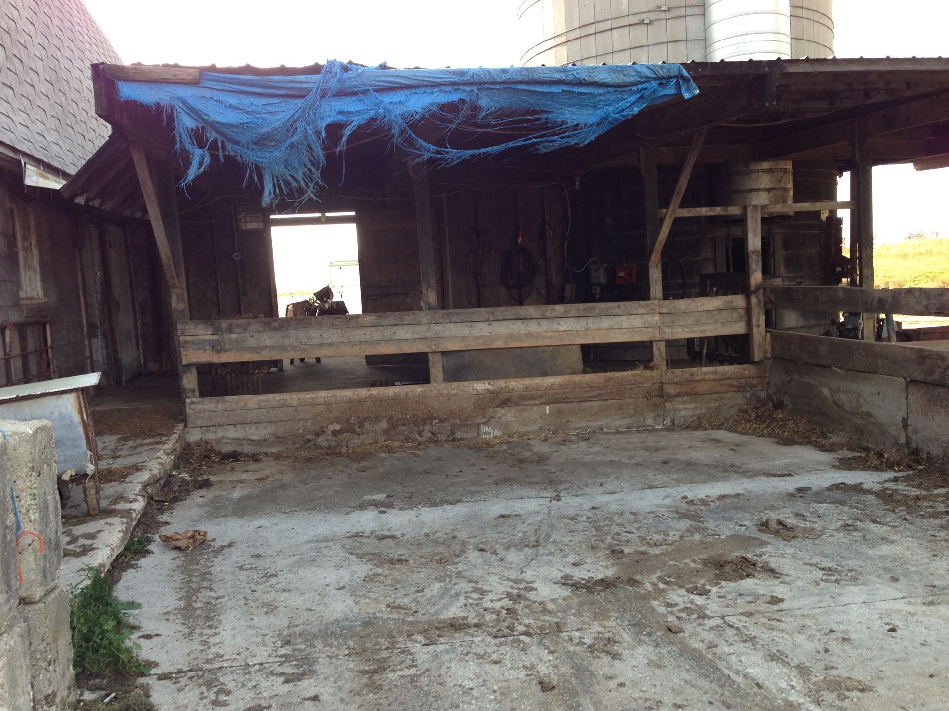 A blue tarp is covering the roof of a barn