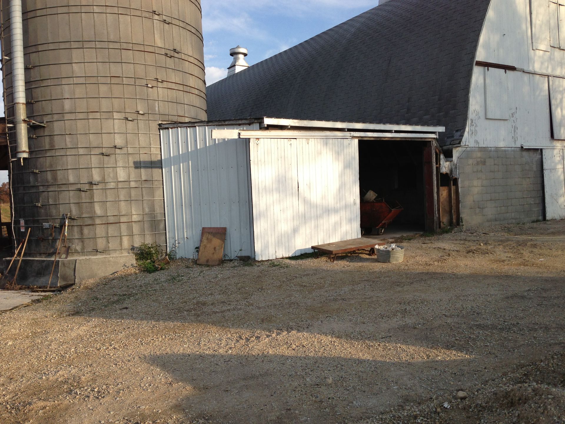 A white barn with a silo in the background