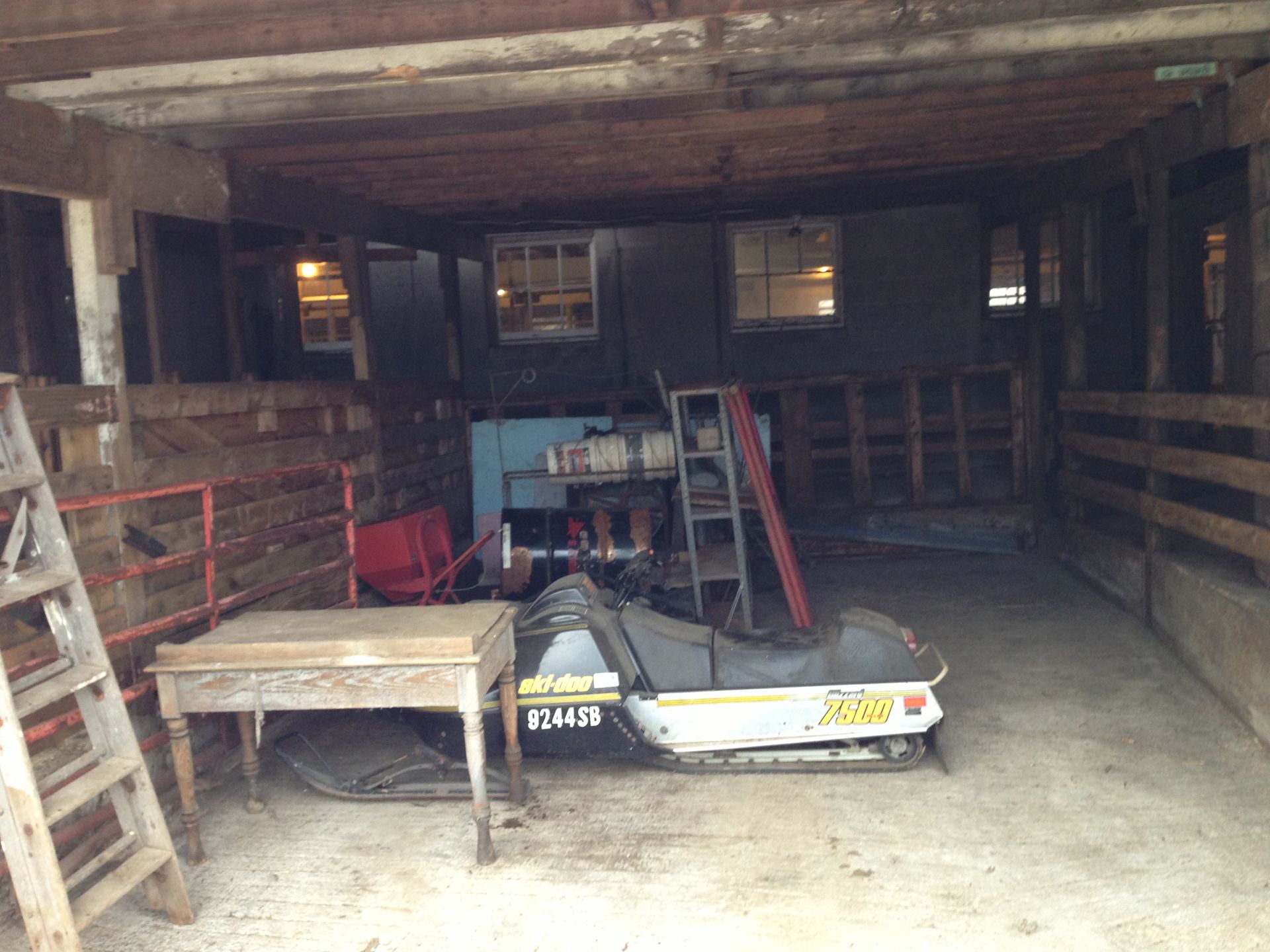 A snowmobile is parked in a barn next to a table.