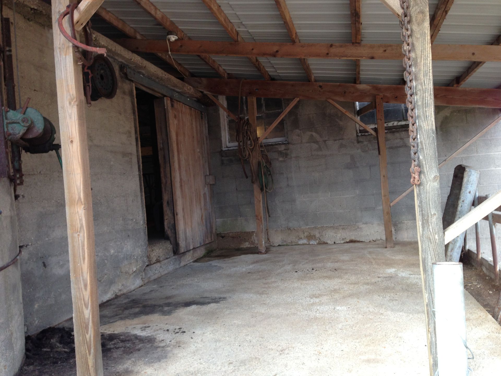An empty barn with a wooden roof and a concrete floor.