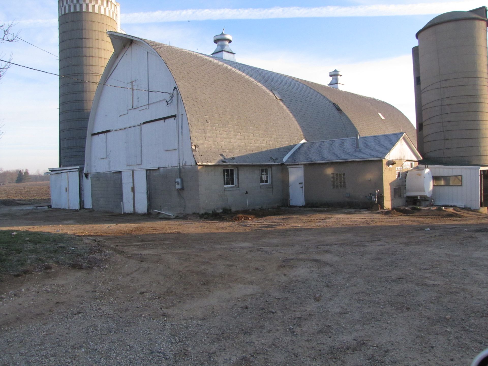 A large barn with two silos in the background