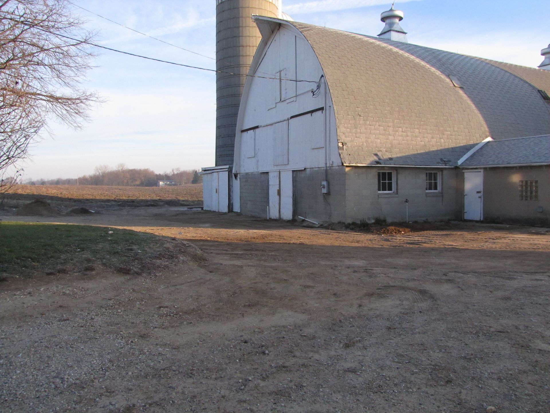 A large barn with a silo in the background