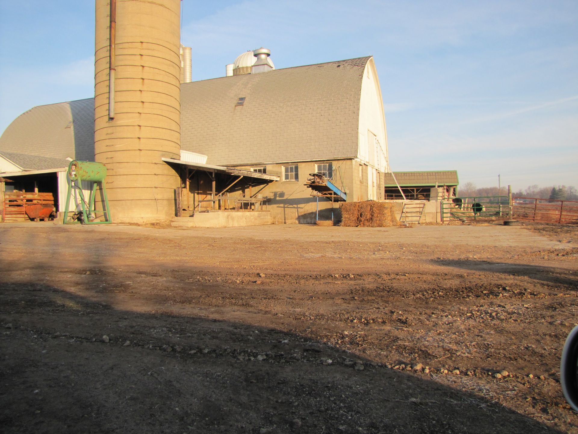 A large barn with a silo in front of it